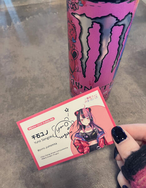 Yuno showing off her signed business card with her favorite pink Monster Energy in the background